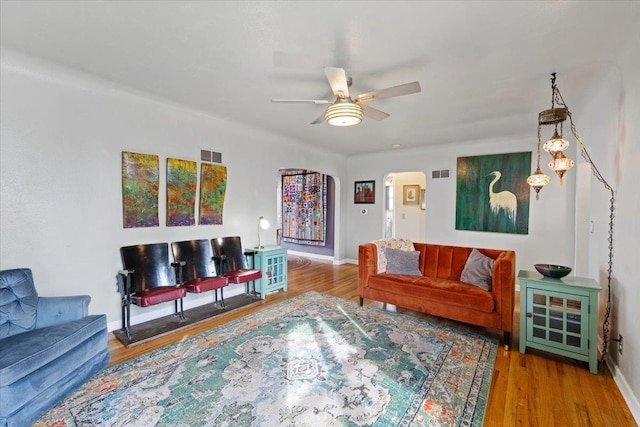 living room featuring visible vents, arched walkways, wood finished floors, and a ceiling fan