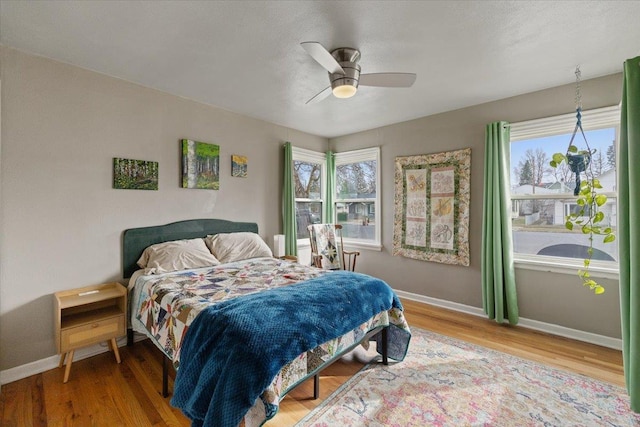 bedroom featuring baseboards, multiple windows, and wood finished floors