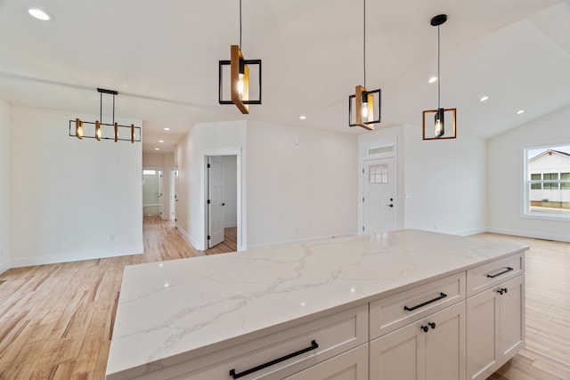 kitchen featuring light stone counters, open floor plan, white cabinetry, and light wood-style floors