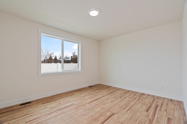 spare room featuring visible vents, baseboards, and wood finished floors