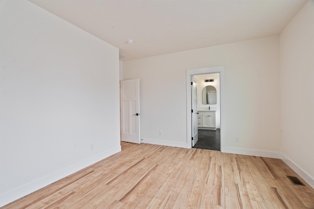 unfurnished room with visible vents, baseboards, and hardwood / wood-style floors