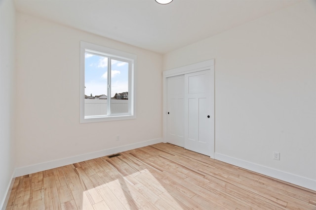 unfurnished bedroom featuring visible vents, wood finished floors, baseboards, and a closet