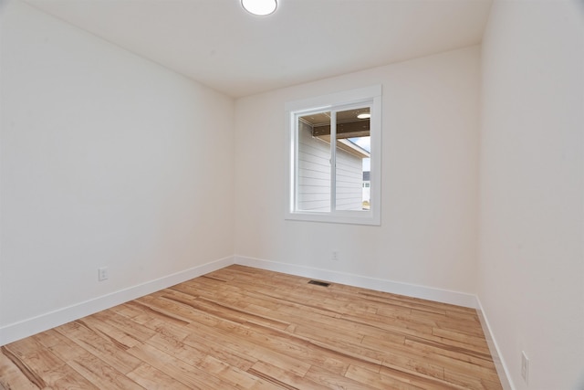 empty room with light wood-style flooring, baseboards, and visible vents