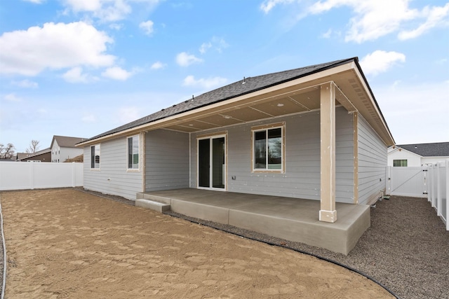 rear view of house with a fenced backyard, a patio, and a gate