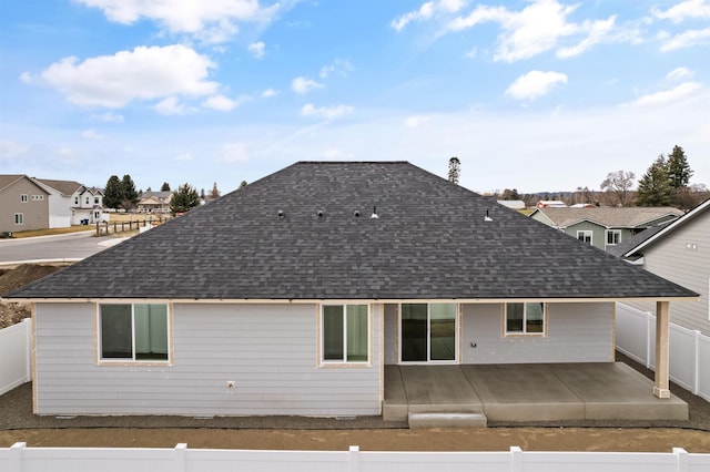 rear view of house featuring a patio, a fenced backyard, and a shingled roof