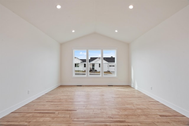 spare room featuring recessed lighting, light wood-type flooring, lofted ceiling, and baseboards