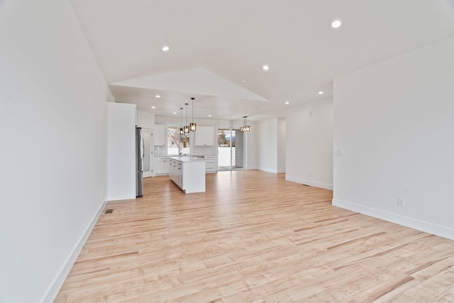 unfurnished living room with light wood finished floors, baseboards, vaulted ceiling, recessed lighting, and a notable chandelier