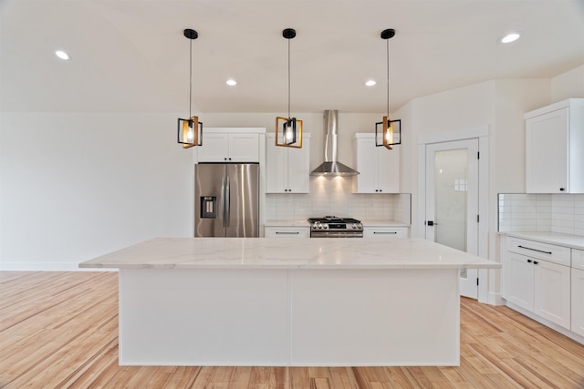 kitchen with a center island, wall chimney range hood, stainless steel fridge with ice dispenser, light wood-style floors, and stove