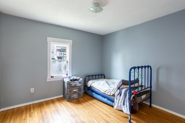 bedroom featuring baseboards, wood-type flooring, and a textured ceiling