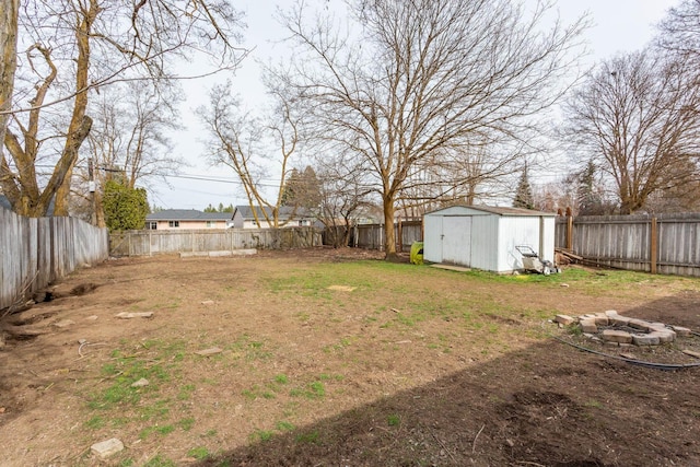 view of yard with a fenced backyard, an outdoor fire pit, an outdoor structure, and a shed