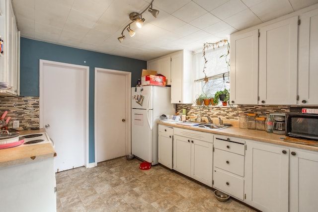 kitchen with a sink, white cabinetry, light countertops, and freestanding refrigerator