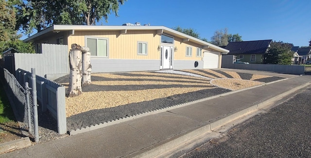 view of front of house with driveway, a garage, and fence