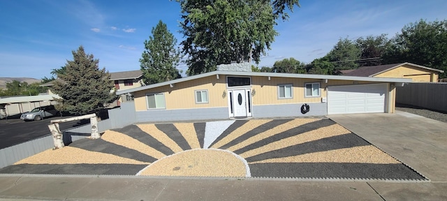 view of front facade featuring a garage, concrete driveway, and fence