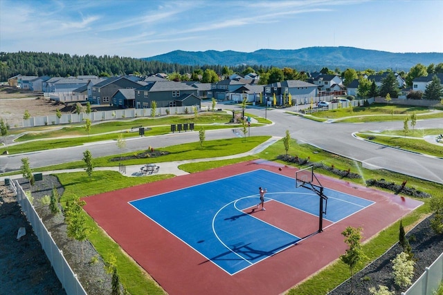 view of sport court featuring community basketball court, a mountain view, fence, and a residential view