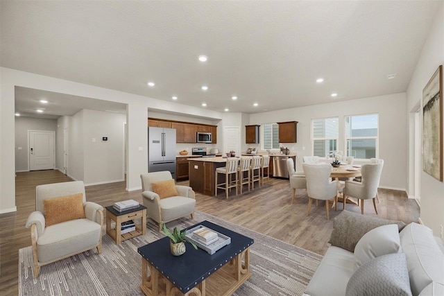 living room with recessed lighting, light wood-type flooring, and baseboards