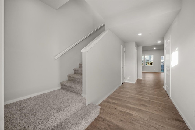 staircase featuring recessed lighting, baseboards, and wood finished floors