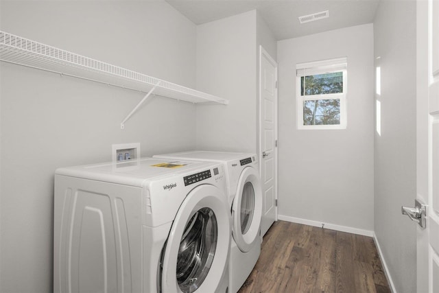 clothes washing area featuring visible vents, dark wood-type flooring, washing machine and dryer, baseboards, and laundry area