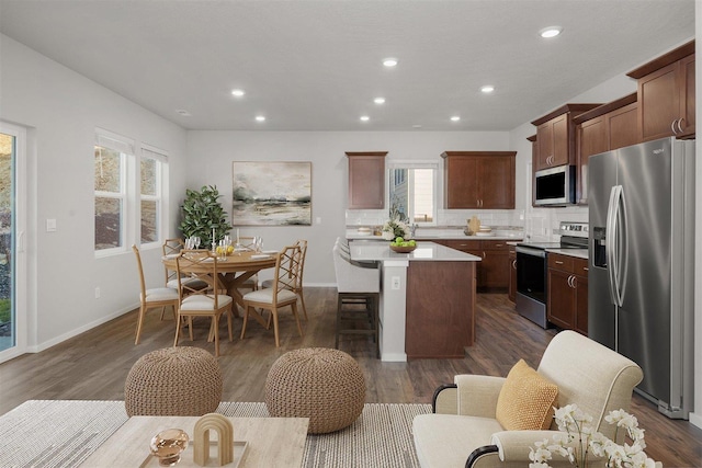 kitchen featuring tasteful backsplash, dark wood finished floors, a center island, stainless steel appliances, and light countertops