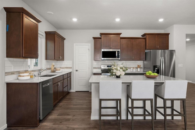 kitchen featuring a center island, dark wood finished floors, light countertops, stainless steel appliances, and a sink