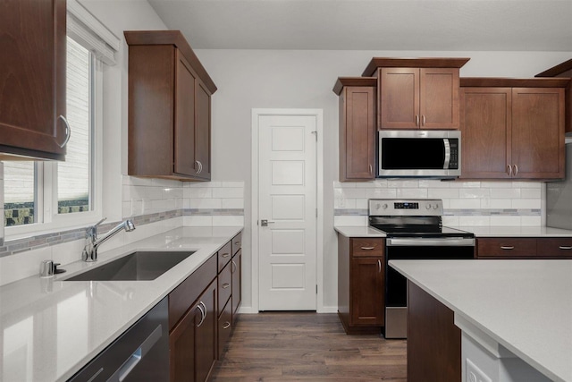 kitchen with a sink, dark wood-type flooring, light countertops, and stainless steel appliances