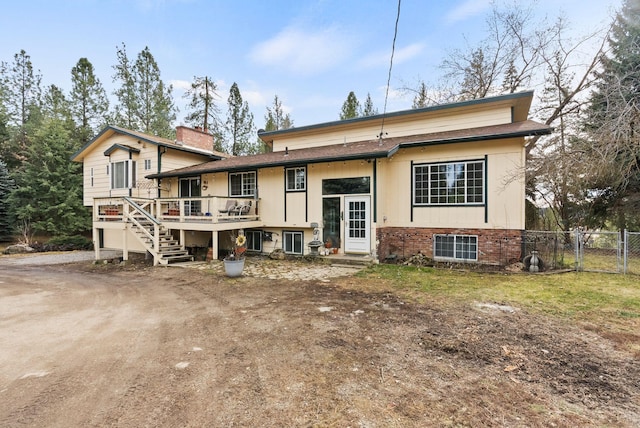 rear view of house featuring stairway, fence, a chimney, a deck, and brick siding