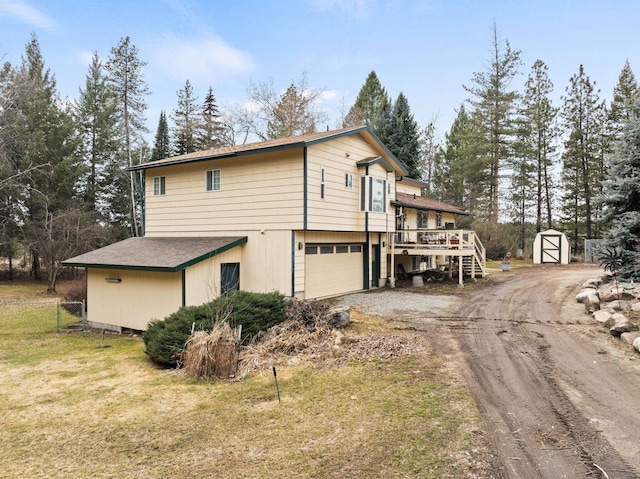 view of side of property featuring fence, a yard, an attached garage, stairs, and dirt driveway