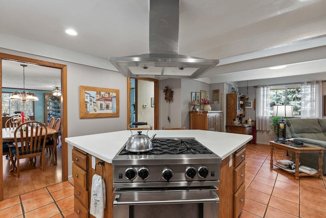 kitchen featuring high end stove, open floor plan, light countertops, brown cabinets, and island range hood