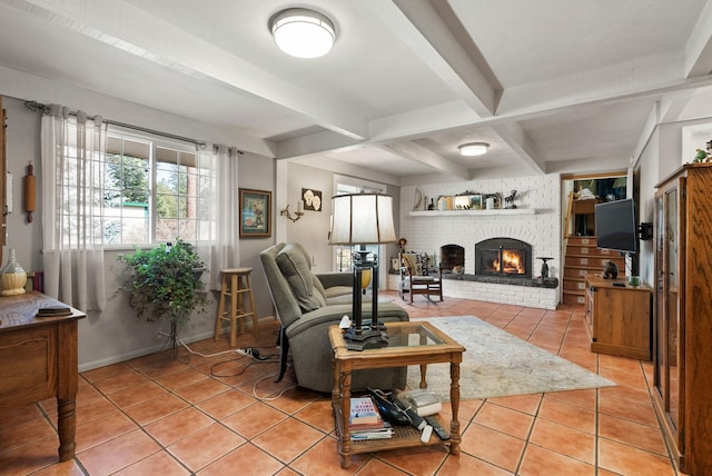 living area with beam ceiling, a brick fireplace, light tile patterned floors, and baseboards