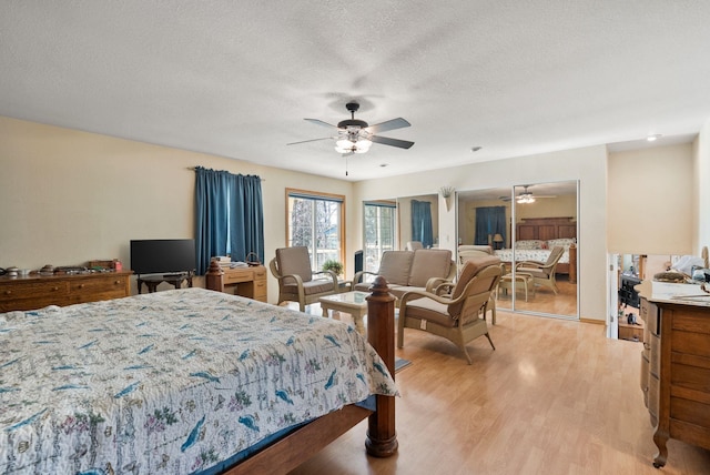 bedroom with light wood-style flooring, a textured ceiling, and ceiling fan