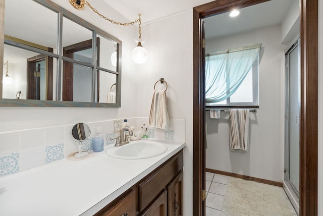 bathroom featuring a shower with door, baseboards, vanity, and tile patterned flooring