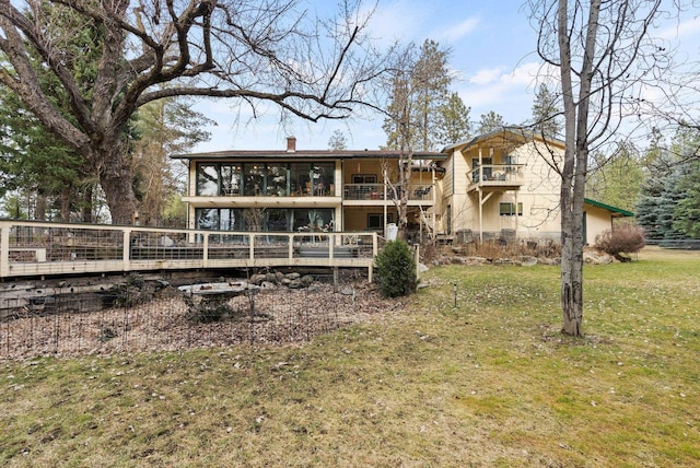 back of property with a deck, a lawn, a balcony, and a chimney