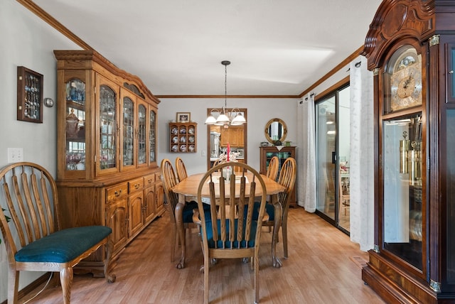 dining space featuring light wood finished floors, a chandelier, and ornamental molding