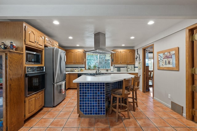 kitchen with visible vents, island exhaust hood, a center island, stainless steel appliances, and light tile patterned floors