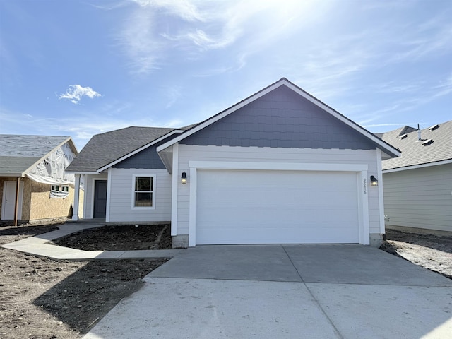 ranch-style home featuring a garage, roof with shingles, and driveway