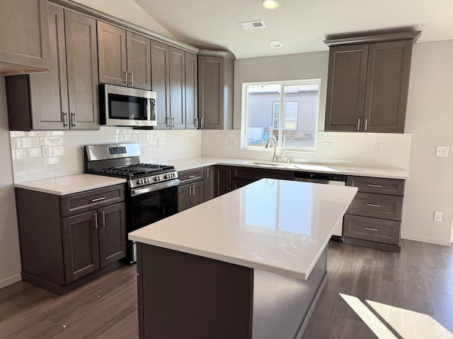 kitchen with visible vents, dark wood-type flooring, a sink, tasteful backsplash, and stainless steel appliances