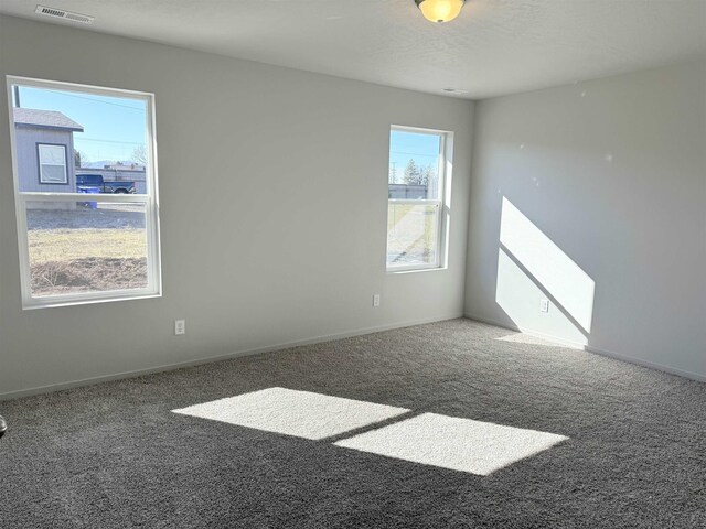 spare room featuring visible vents, baseboards, carpet, and a textured ceiling