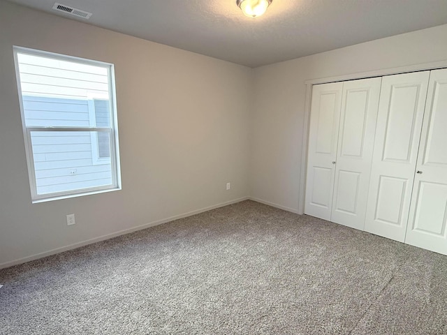 unfurnished bedroom featuring visible vents, baseboards, carpet, a closet, and a textured ceiling