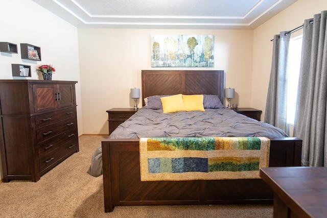 bedroom with a tray ceiling, baseboards, and light carpet