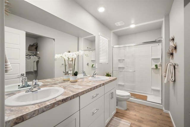 bathroom with a shower stall, wood finished floors, toilet, and a sink