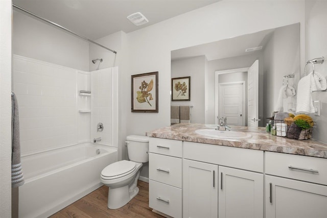 bathroom featuring vanity, wood finished floors, visible vents, shower / washtub combination, and toilet