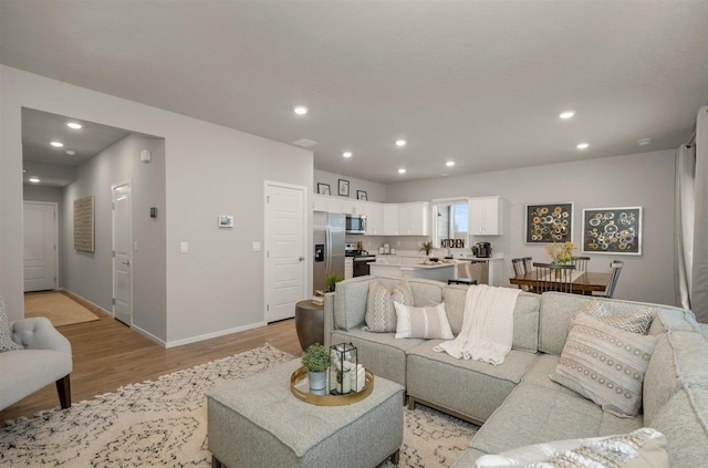 living area with recessed lighting, baseboards, and light wood-style floors