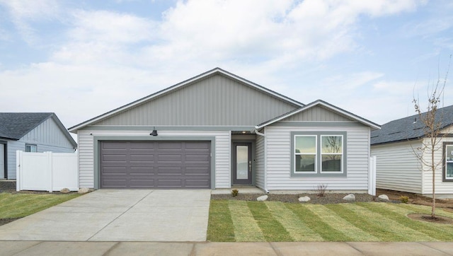 ranch-style home featuring a front lawn, concrete driveway, fence, and a garage