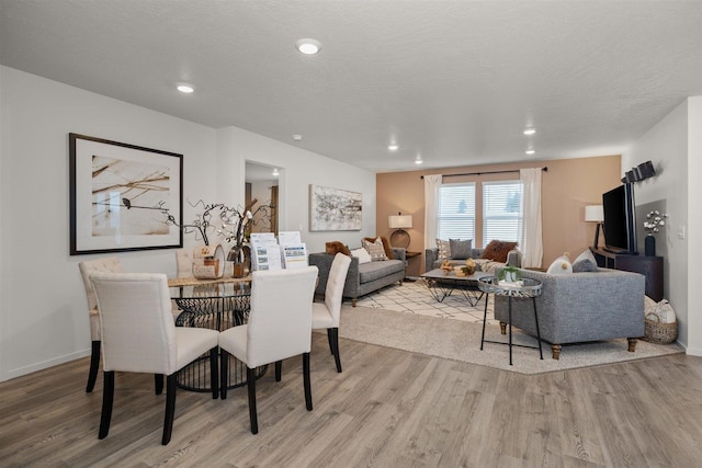 dining area with recessed lighting, a textured ceiling, and wood finished floors