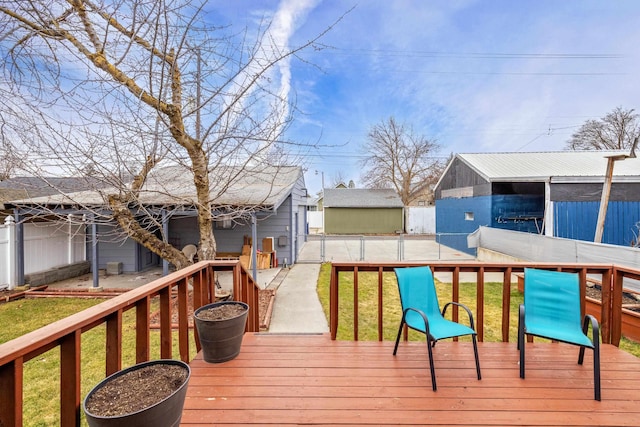 wooden deck featuring an outdoor structure, a yard, and fence