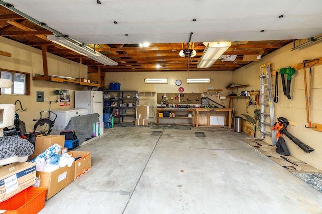 garage with a workshop area, a garage door opener, and freestanding refrigerator