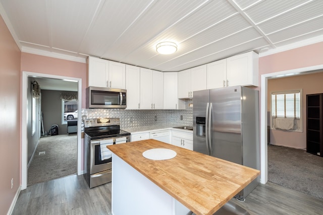 kitchen featuring butcher block countertops, backsplash, appliances with stainless steel finishes, and white cabinets