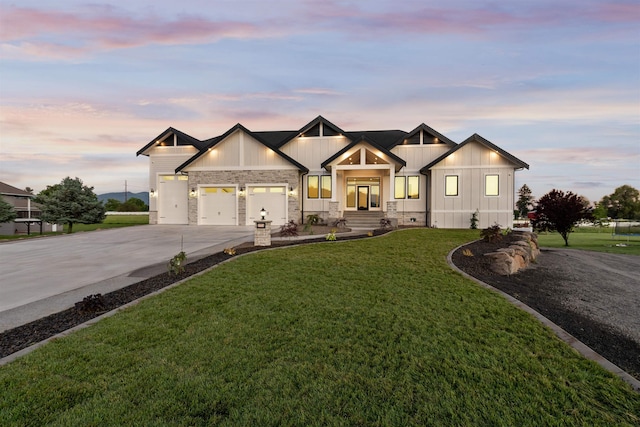 modern inspired farmhouse with driveway, a yard, stone siding, a garage, and board and batten siding