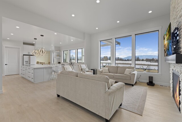 kitchen featuring a sink, light wood-style floors, white cabinets, and wall chimney range hood