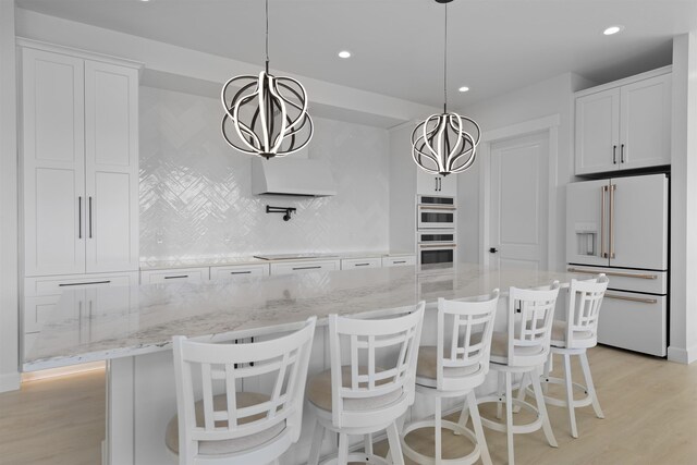 kitchen featuring tasteful backsplash, black electric stovetop, light stone counters, light wood-style floors, and wall chimney exhaust hood