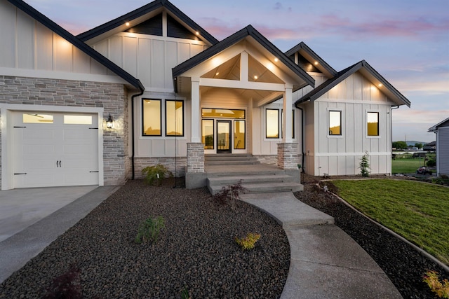 modern inspired farmhouse with stone siding, board and batten siding, and a garage